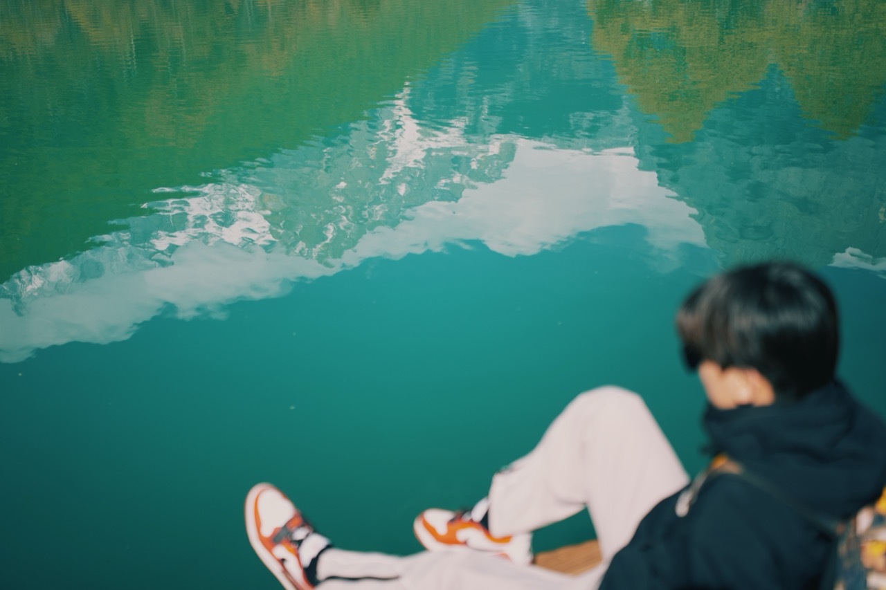 A travel portrait beside turquoise mountain water