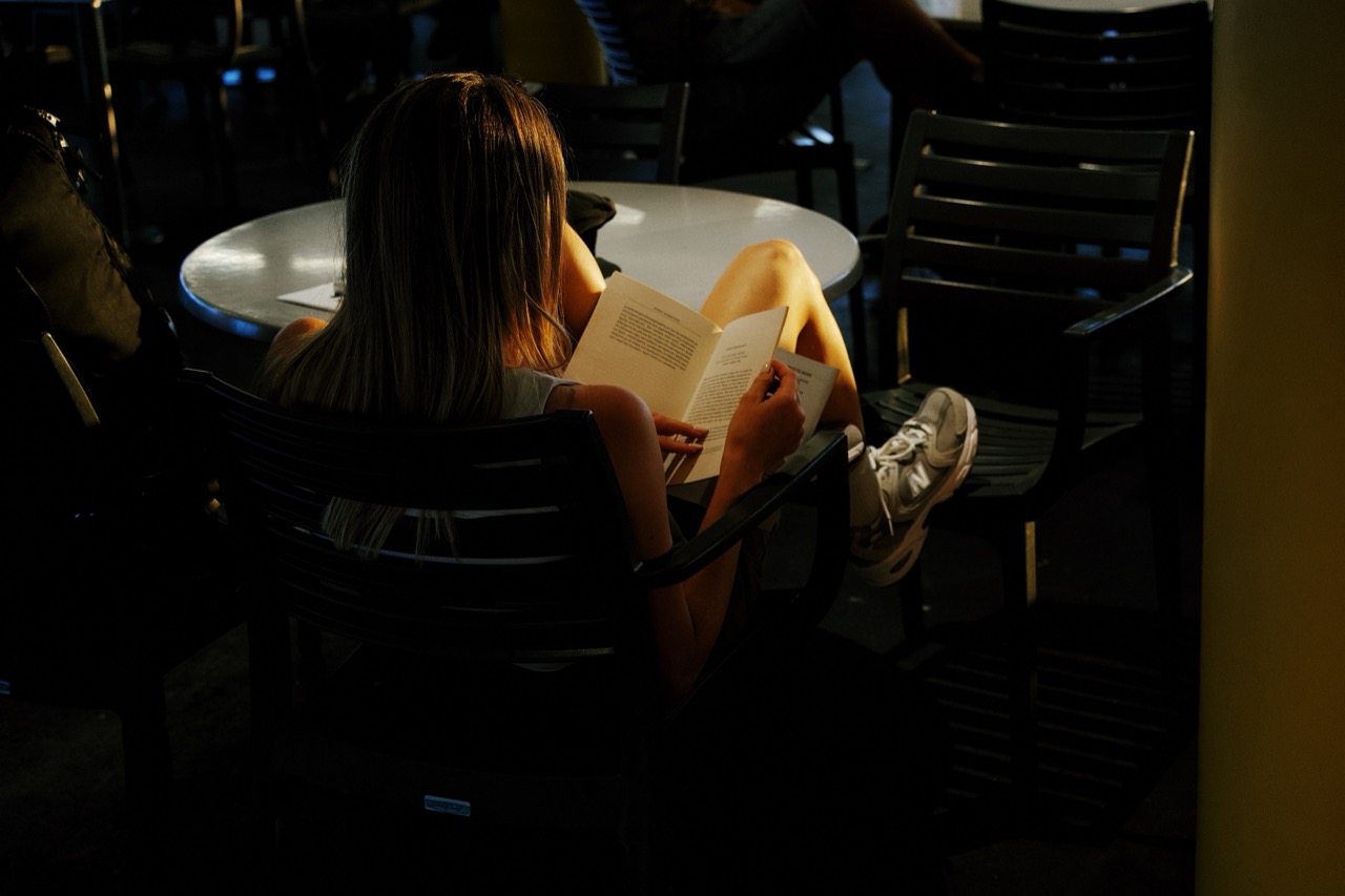 A warm low-light portrait of a person reading during travel